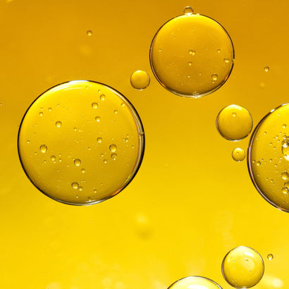 This image features vibrant golden droplets suspended in a clear, luminous oil background, symbolizing the luxurious and nutrient-rich essence of Tsubaki (camellia) oil. Renowned for its deeply hydrating and anti-aging properties, Tsubaki oil is rich in essential fatty acids and antioxidants, making it a powerful skincare ingredient. The visual exudes purity, radiance, and vitality, reflecting the transformative benefits it delivers to the skin.